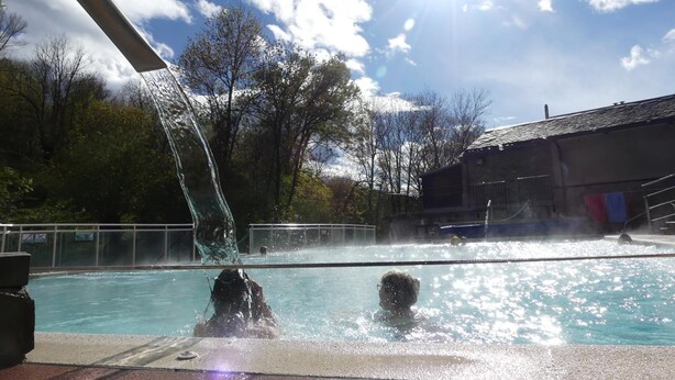 A swimming pool with a water fountain, surrounded by trees and a building. - Gite de Llo (Llo)