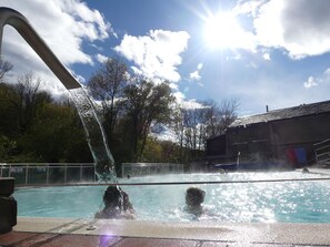 A swimming pool with a water fountain, surrounded by trees and a building. - Gite de Llo (Llo)