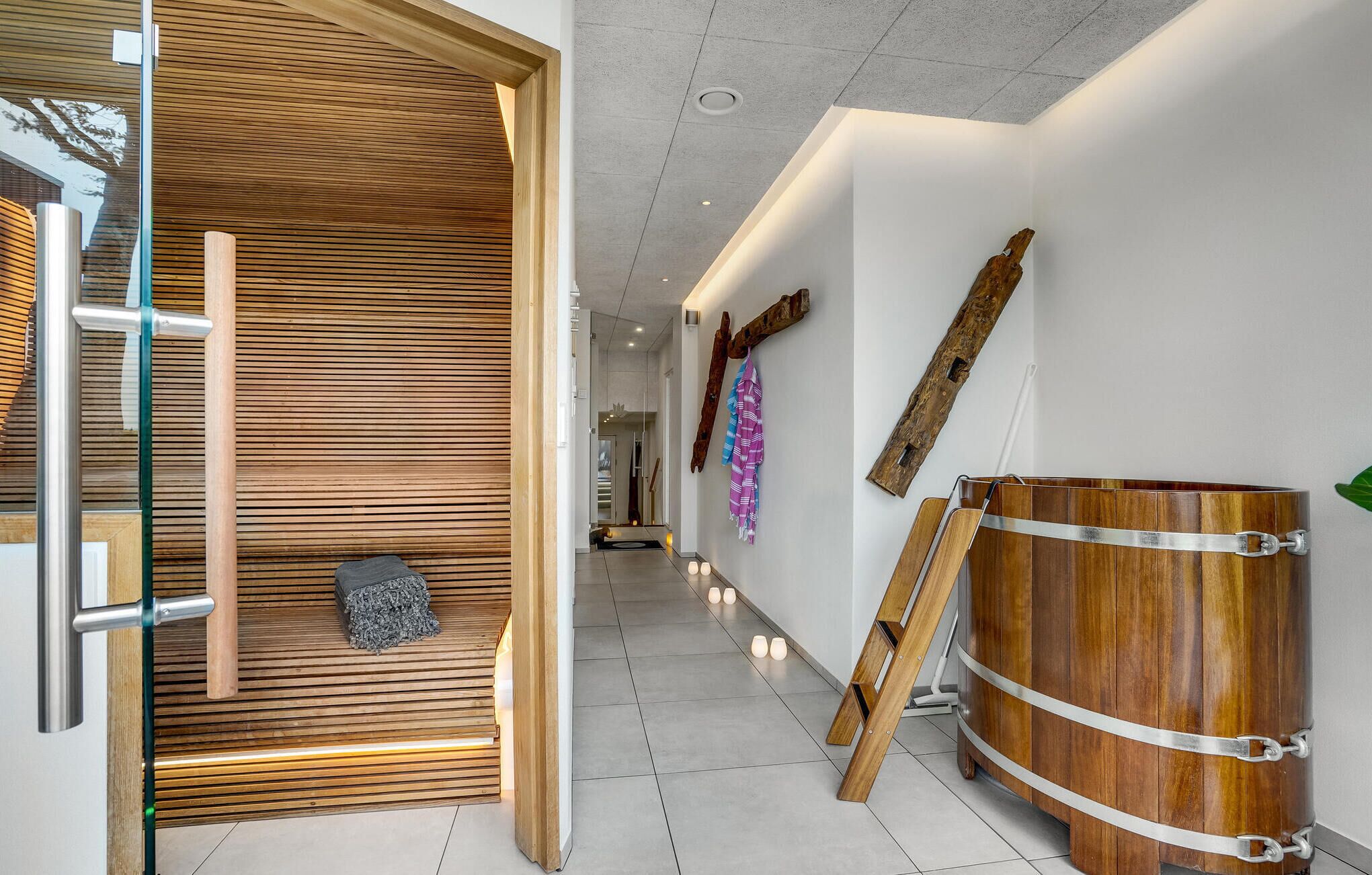 Ein modernes Interieur mit einer Wand aus Holzlatten, einer Glastür und einem Holzbottich mit Metallriemen.