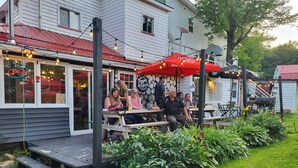 A patio area with wooden benches and tables, surrounded by greenery and a red awning. - Crabbe Mountain Inn (Central Hainesville)