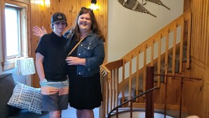 A room with wooden walls, a staircase, a sofa, and a dog. - Crabbe Mountain Inn (Central Hainesville)