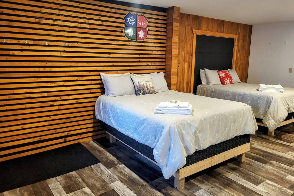 A hotel room with two beds, wooden slat walls, and a coat rack.