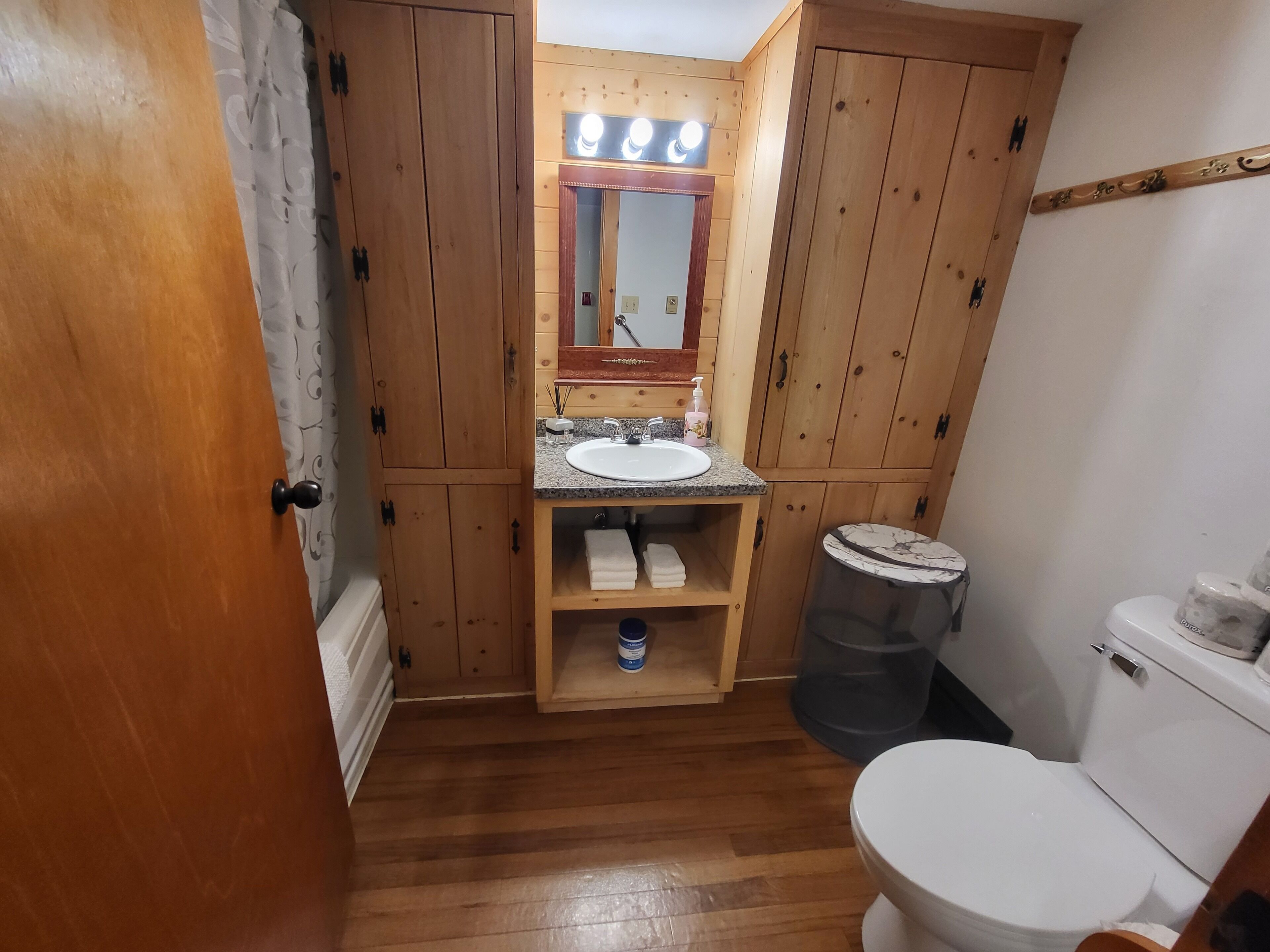 A wooden bathroom with a sink, mirror, and toilet.