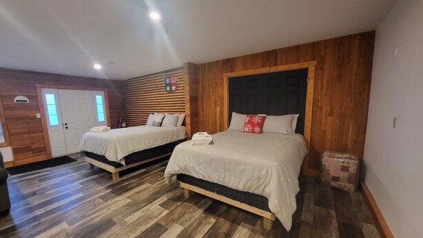 A bedroom with two beds, wooden flooring, and a wooden headboard. - Crabbe Mountain Inn (Central Hainesville)