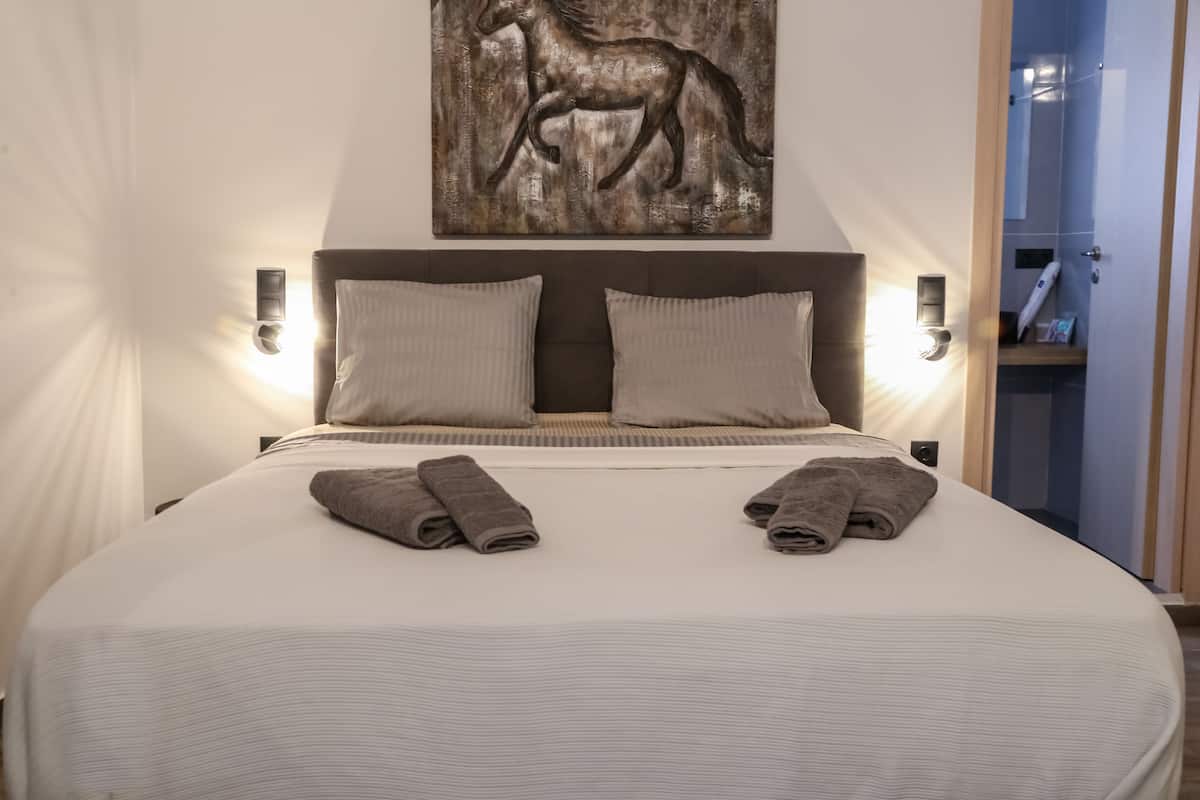 A neatly made bed with two pillows and two folded towels.