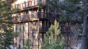 Une cabane en bois à plusieurs étages, dotée de balcons et entourée d’arbres et de neige.