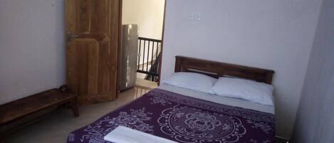 Una camera da letto con un letto, una panca in legno e un armadio.