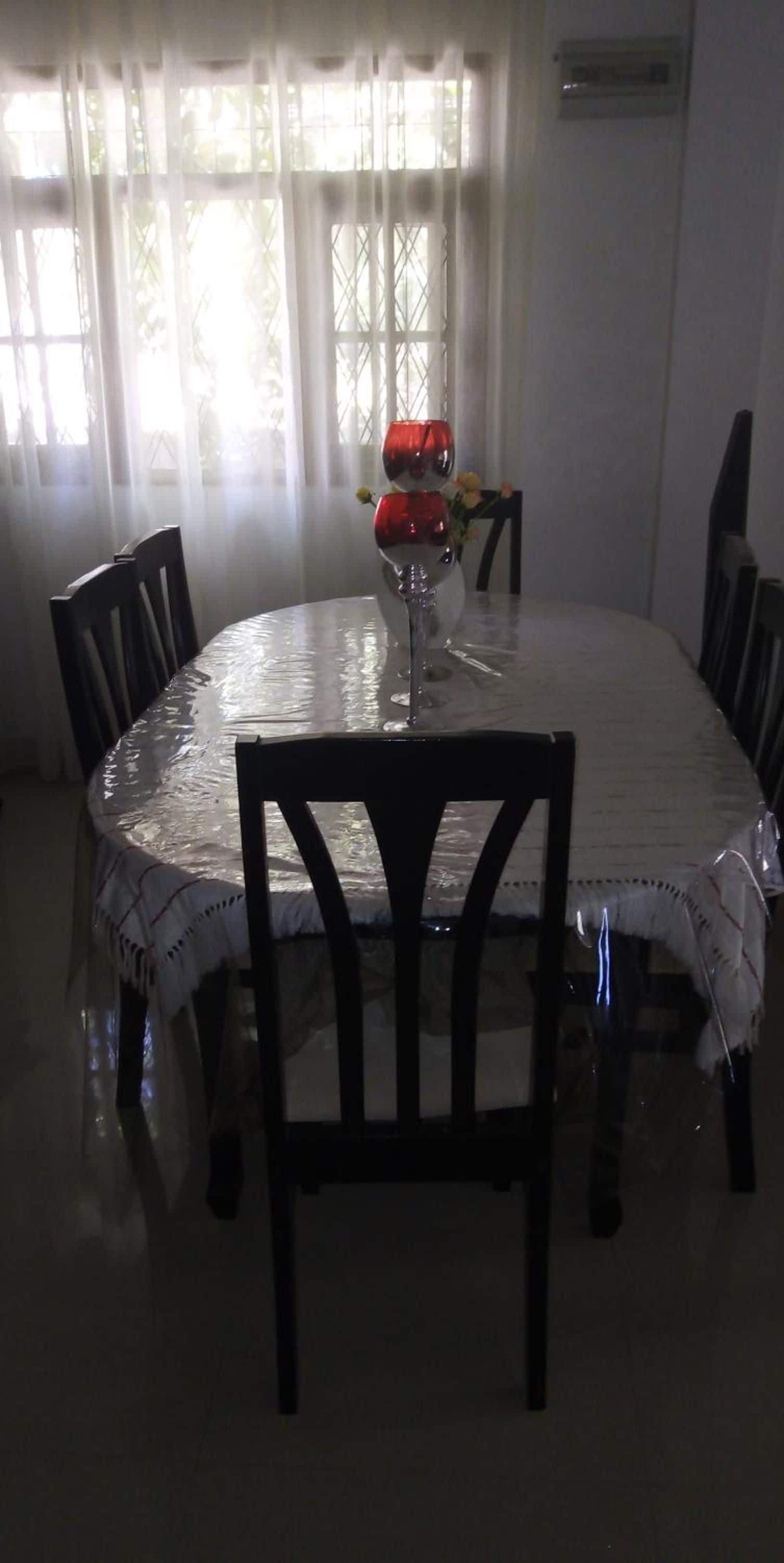 A round dining table with a white tablecloth, surrounded by chairs.