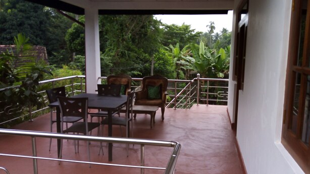 A covered outdoor seating area with a table and chairs, surrounded by lush greenery. - Senuri Home stay (Polonnaruwa)
