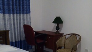 A bedroom with a wooden bed, a desk, a chair, and a lamp. - Senuri Home stay (Polonnaruwa)