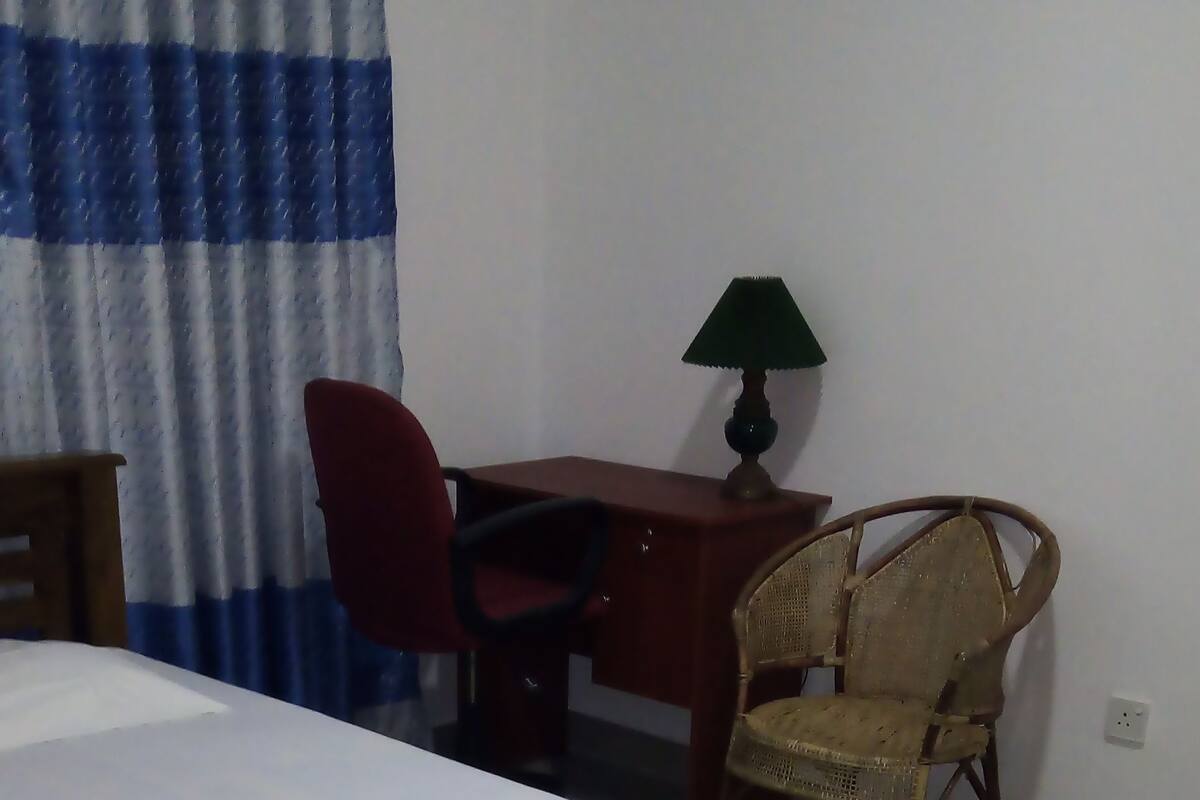 Ein Schlafzimmer mit einem hölzernen Bett, einem Schreibtisch, einem Stuhl und einer Lampe.