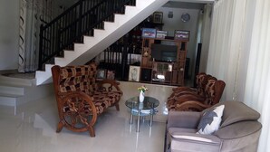 A living room with a staircase, wooden furniture, a glass coffee table, and a television. - Senuri Home stay (Polonnaruwa)