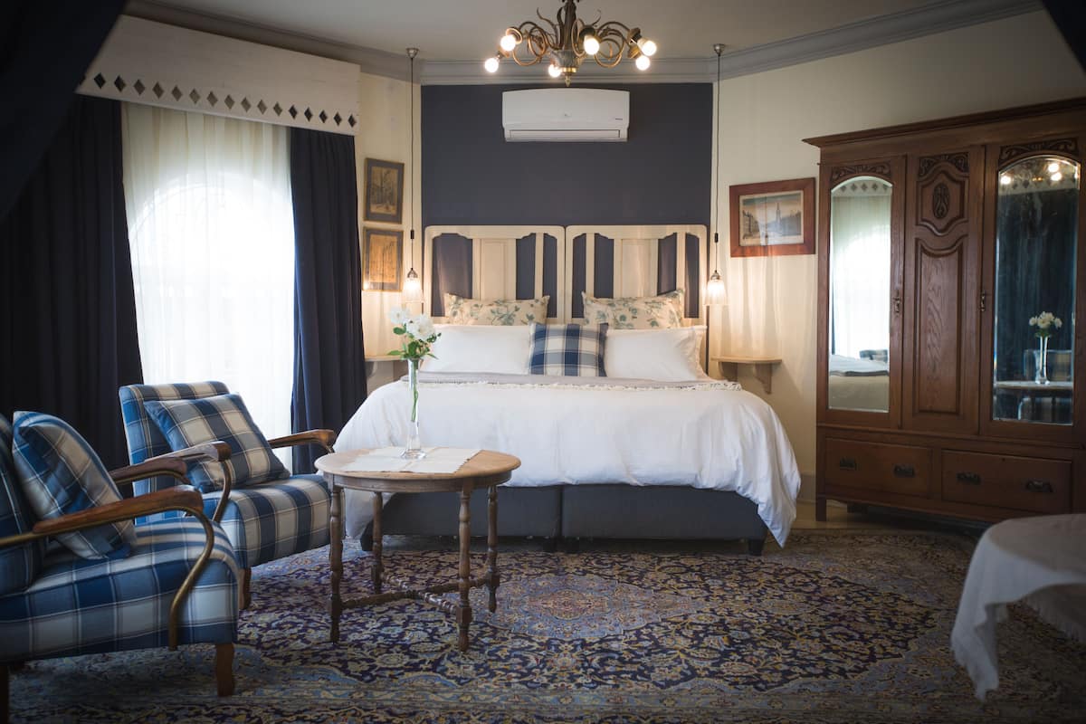 Une chambre avec un grand lit, une armoire en bois, une chaise et une petite table.