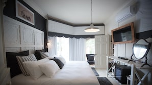Une chambre avec un grand lit, un bureau doté d’un miroir et un téléviseur.