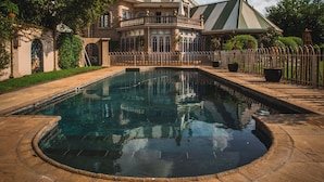 Une grande maison somptueuse, avec une piscine en premier plan.