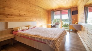 A cozy wooden cabin room with a bed, a desk, and a chair.