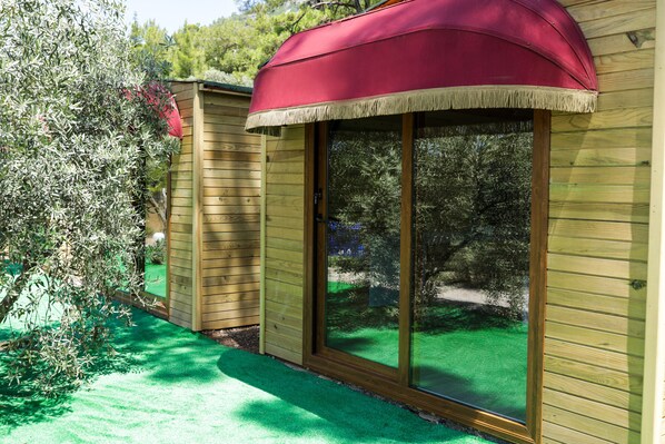 A wooden building with a sliding glass door and a red awning. - Akyaka - Akbuk Fullmoon Bungalow Camping (Mugla)