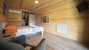 A wooden cabin room with a bed, a small table, and a sofa.