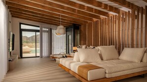 A modern bedroom with a wooden ceiling, a large bed, a TV, and a view of a mountainous landscape. - Villa Calma (Agios Nikolaos)