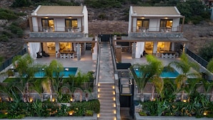 A modern two-story house with a central pool, surrounded by lush greenery and a stone pathway. - Villa Calma (Agios Nikolaos)