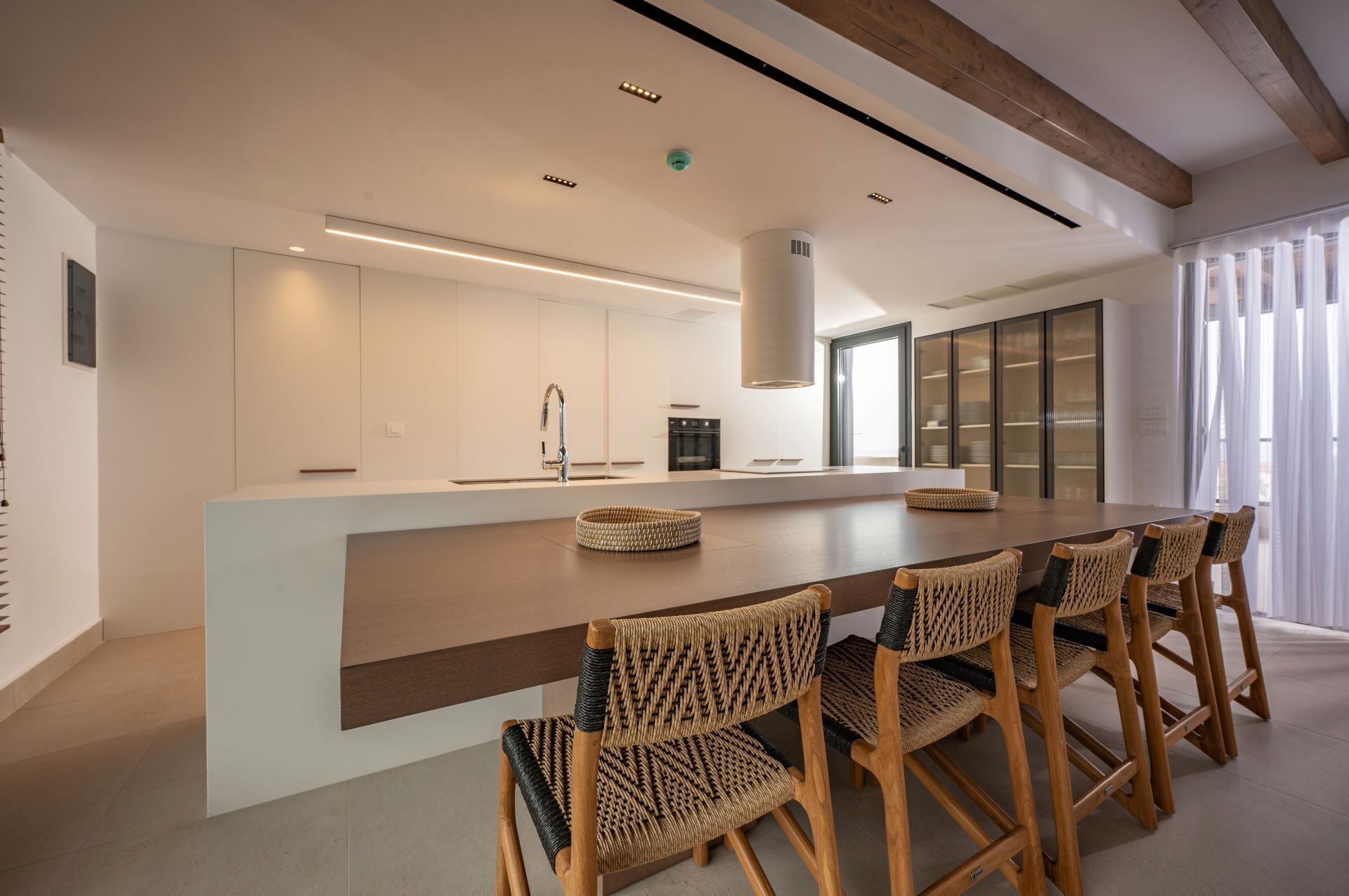 Una cocina moderna con una isla central, electrodomésticos integrados y un amplio ventanal.
