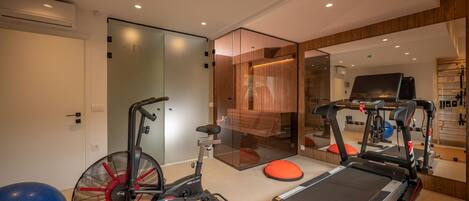 Un gimnasio en casa con cinta de correr, bicicleta estática y pelota de ejercicios.