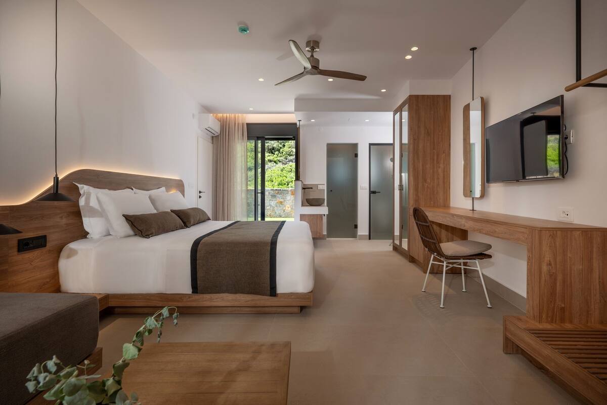 A modern bedroom with a large bed, a desk, and a television.