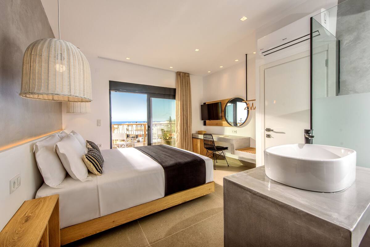A modern bedroom with a bed, bedside table, and a large window.