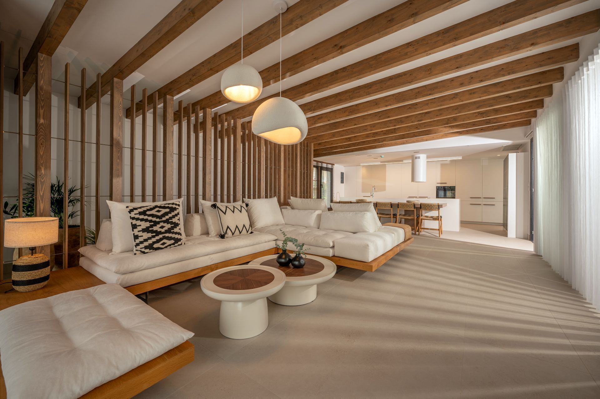 A modern living room with a sectional sofa, two round coffee tables, and a dining area in the background.