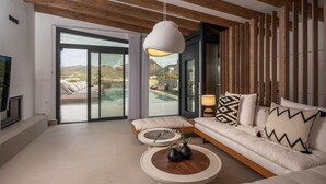 A modern living room with a sofa, a round coffee table, and a hanging light fixture. - Villa Calma (Agios Nikolaos)