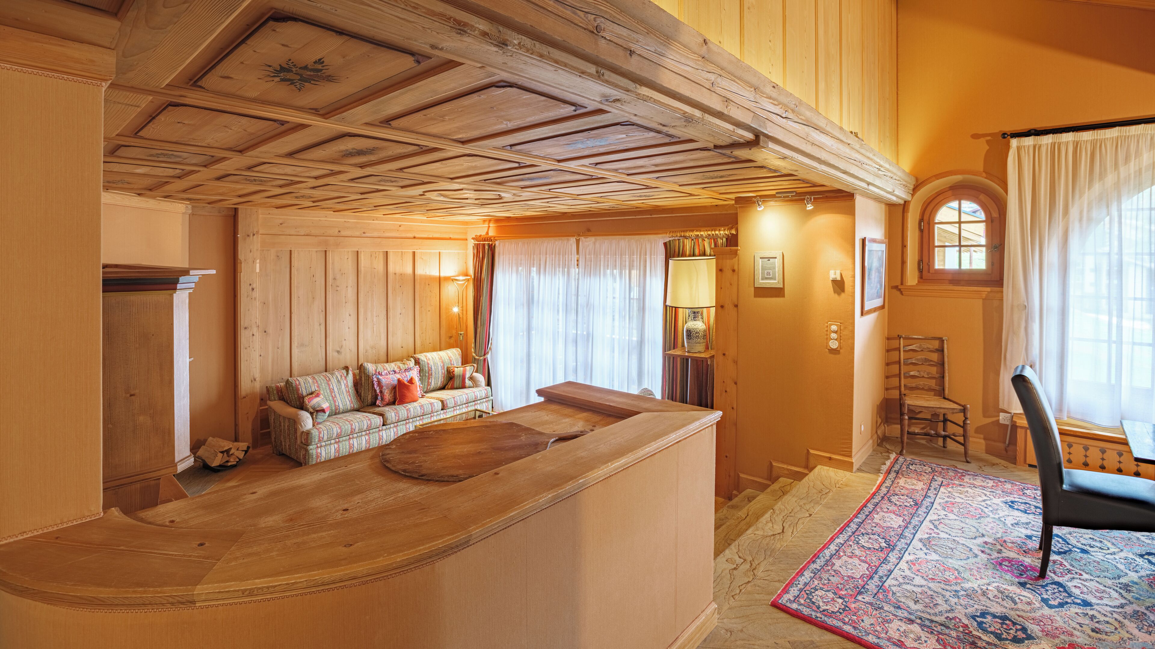A wooden interior with a sofa, a wooden bench, and a rug.