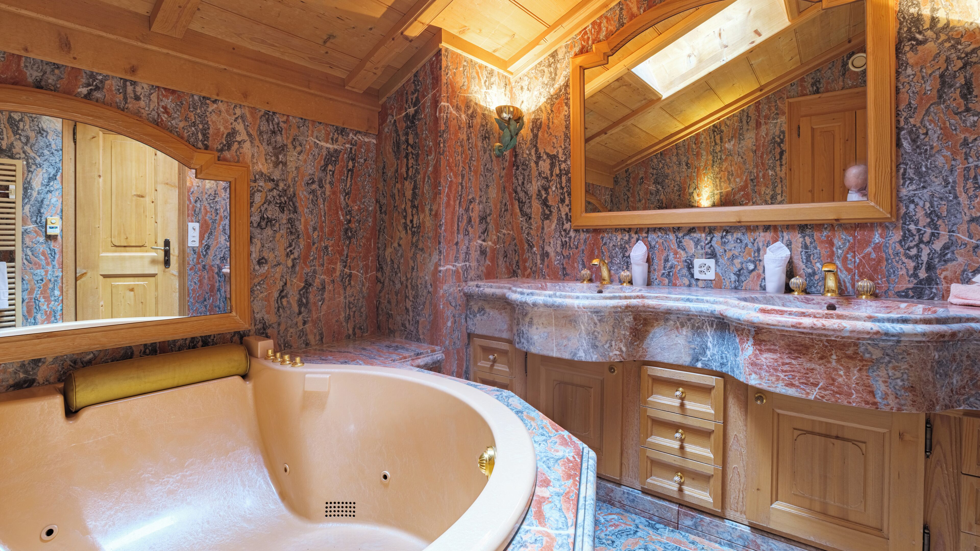 A bathroom with a freestanding bathtub, marble countertops, wooden cabinets, and a large mirror.