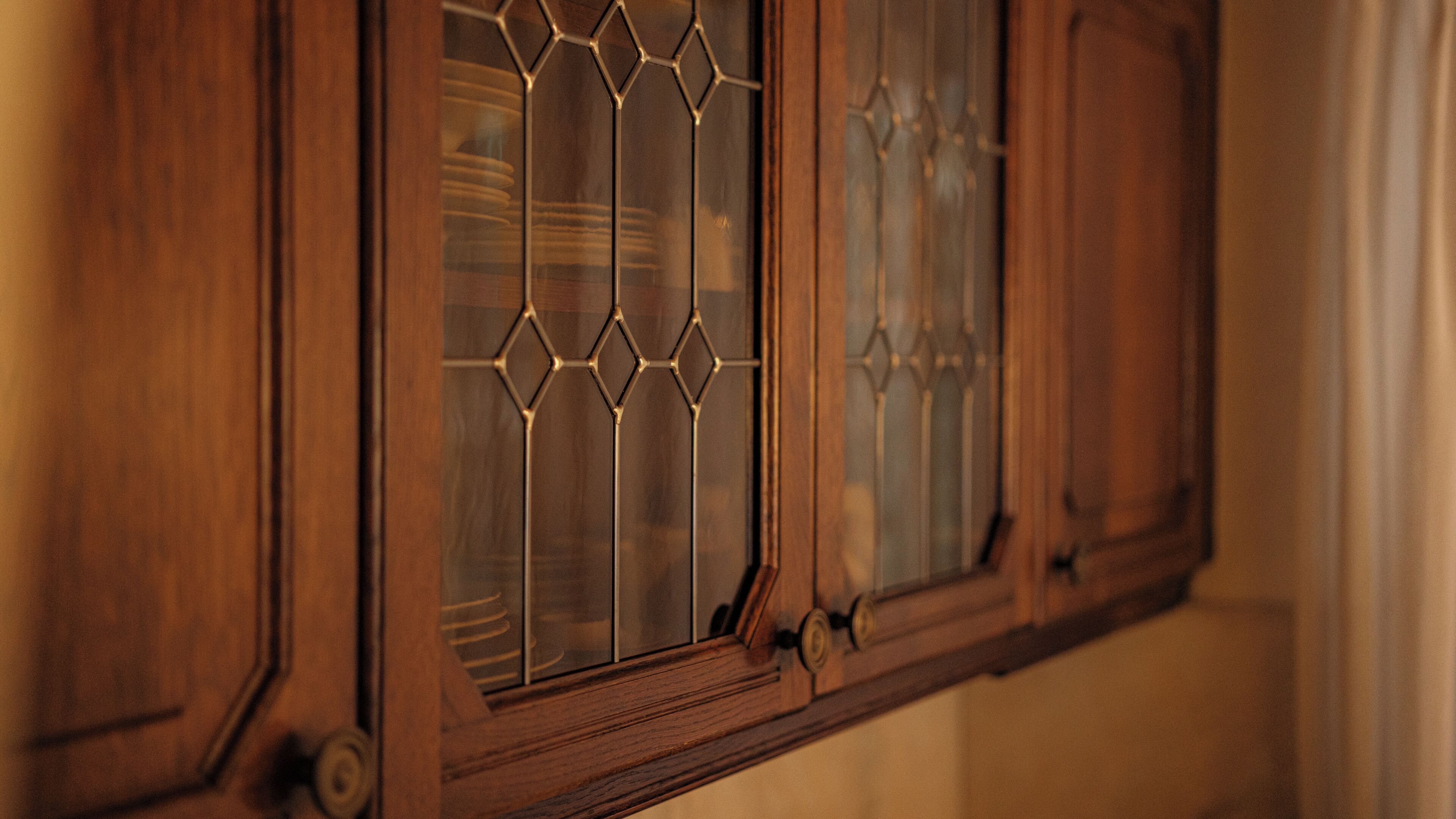 Un meuble en bois doté d’une porte en verre ornée de motifs en forme de losanges.