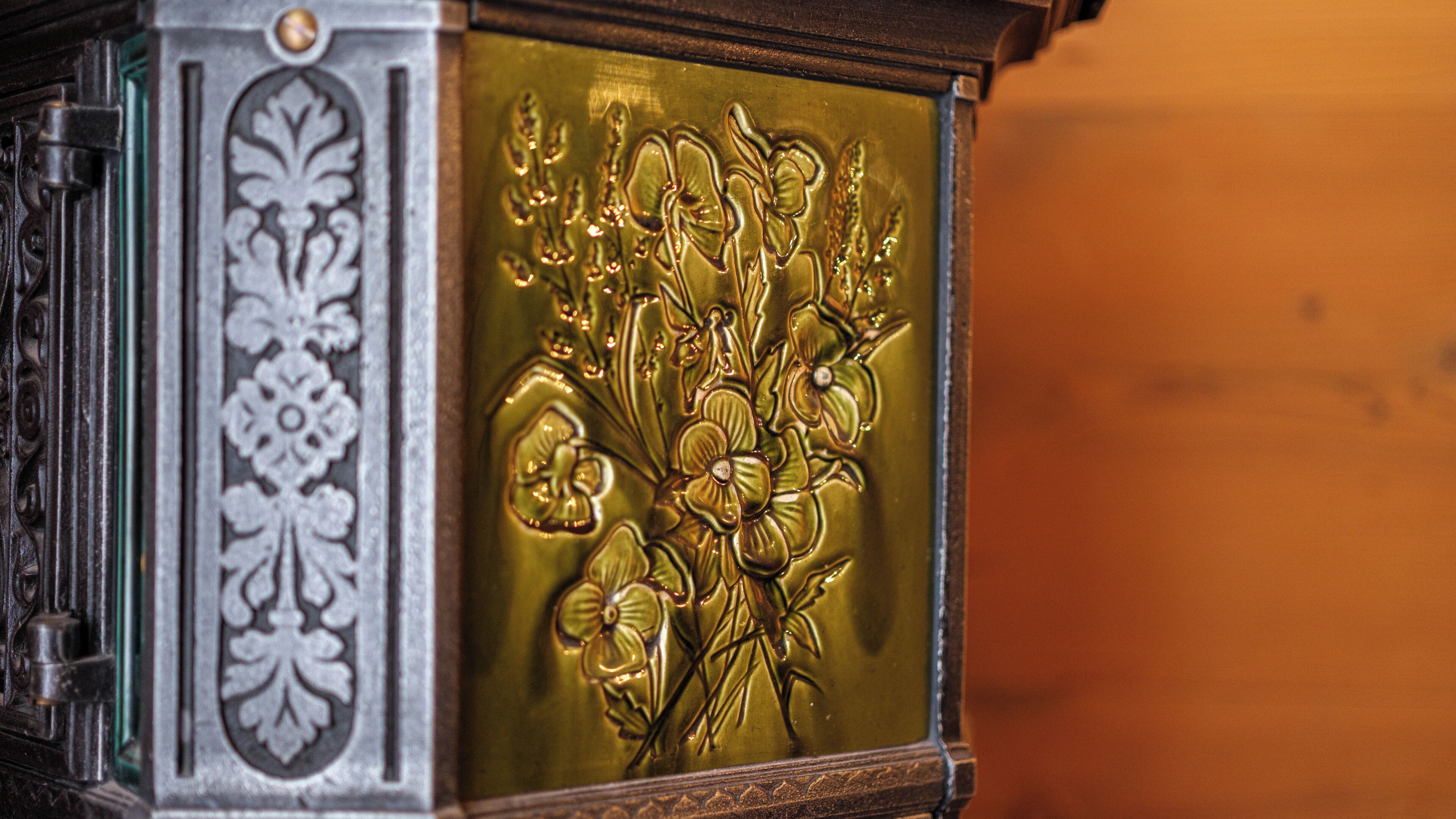 A close-up of a decorative panel with floral engravings and a metallic finish.