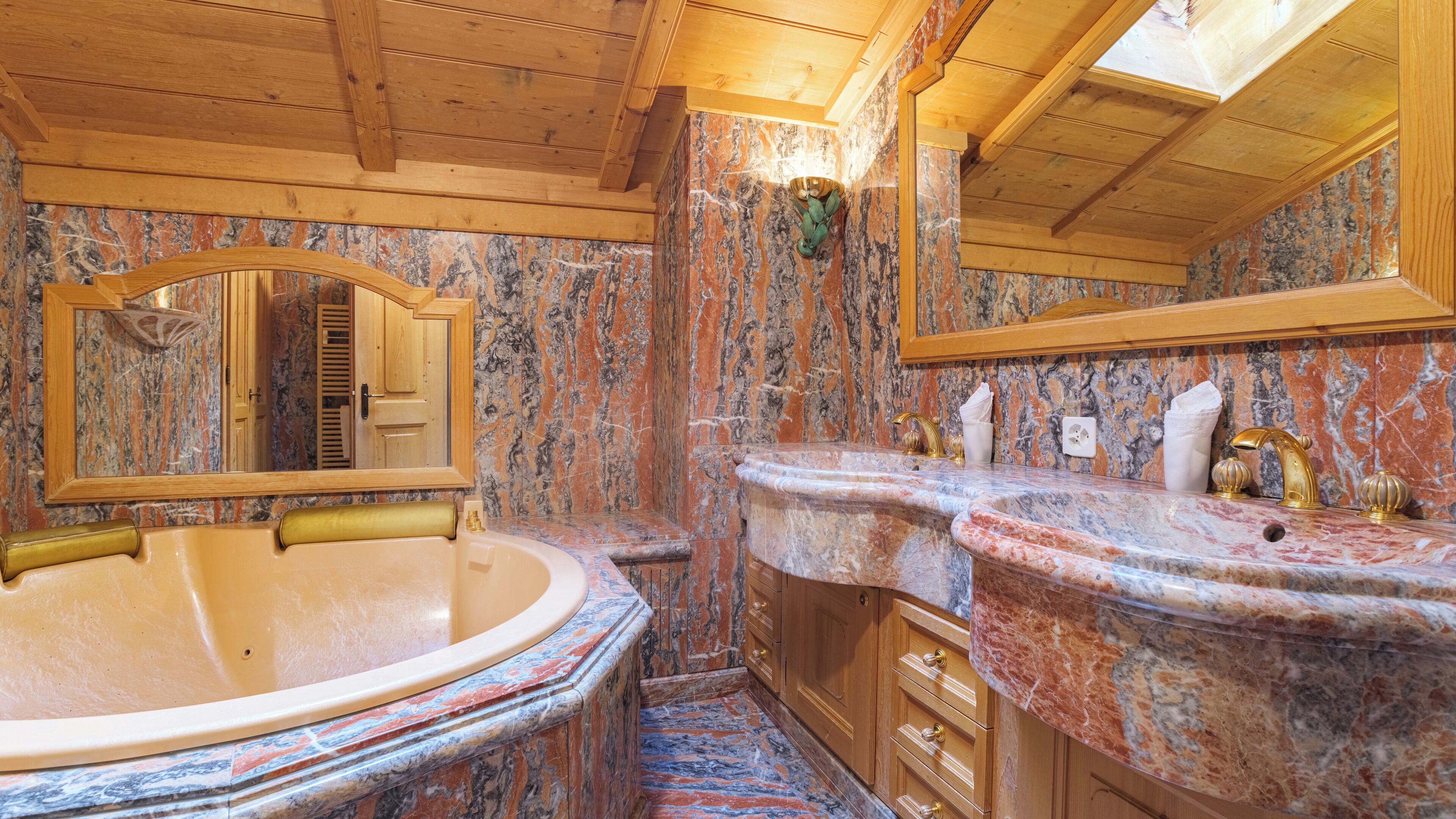 A bathroom with a freestanding bathtub, marble countertops, wooden cabinets, and a large mirror.