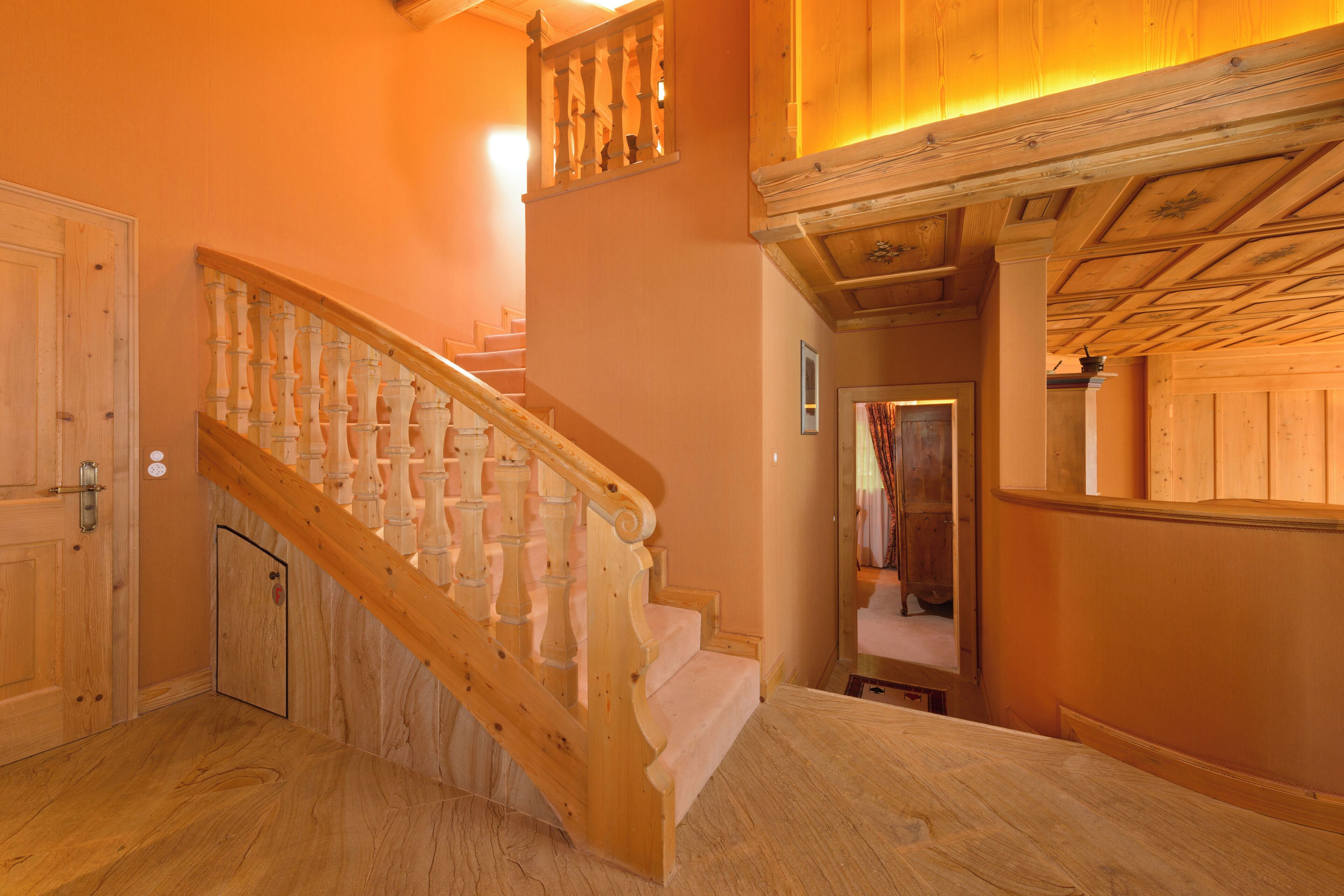 A wooden staircase with a handrail, wooden walls, and a ceiling with exposed beams.