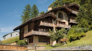 A traditional wooden chalet with multiple balconies, stone walls, and a sign indicating 'Riessee'. - Chalet Kisseye by Zermatt Premium Apartments (Zermatt)