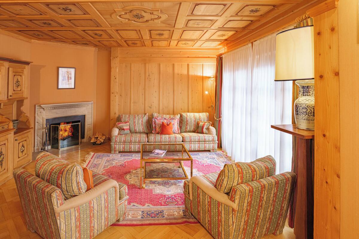 A cozy living room with a fireplace, patterned sofas, and a coffee table.