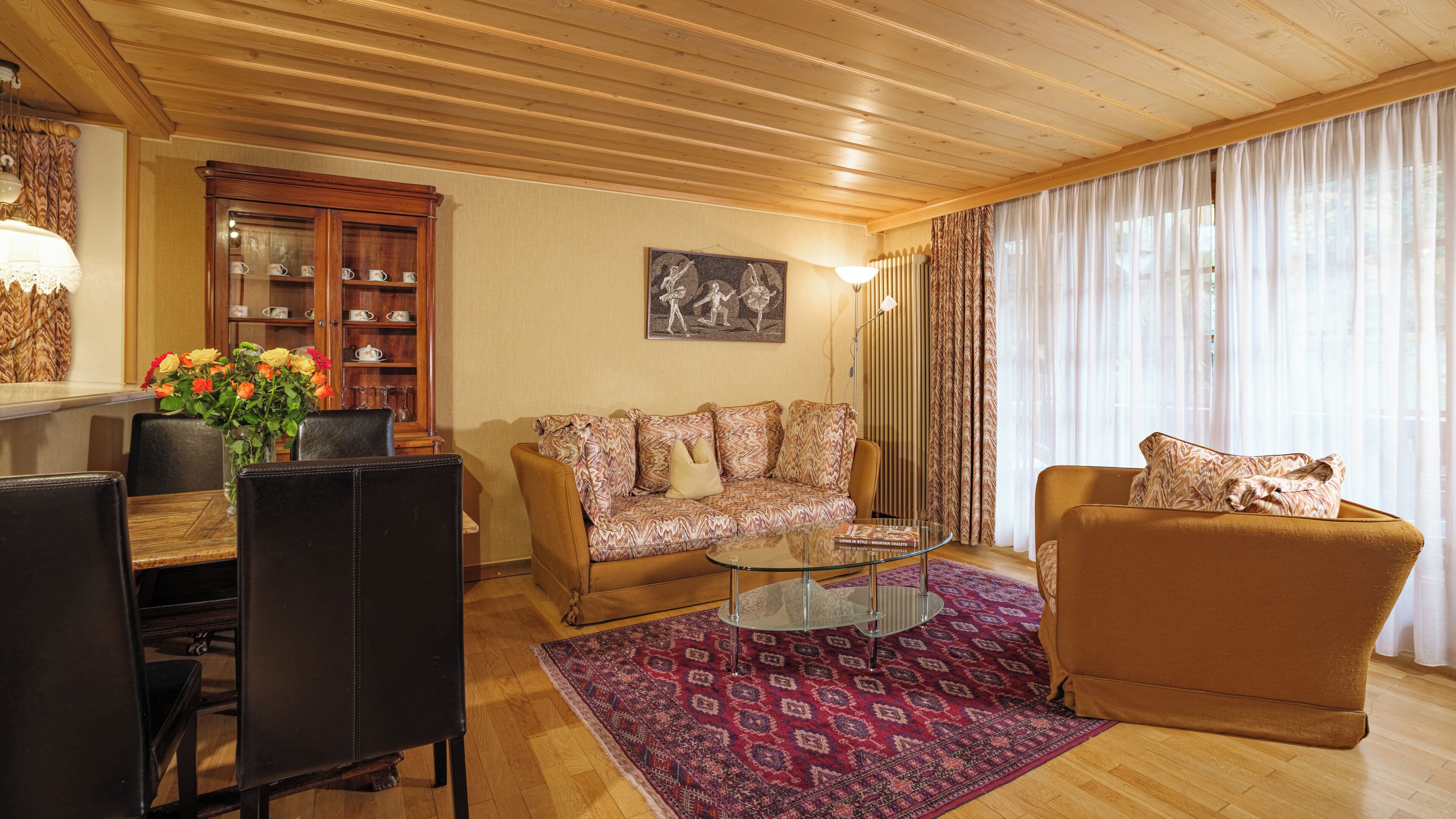 Una sala de estar con techo de madera, un sofá, una mesa de centro y un comedor con sillas y una mesa.