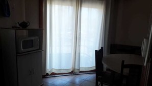 A kitchen with a microwave, a cabinet, and a table with chairs. - Departamentos MTD (Balcarce)