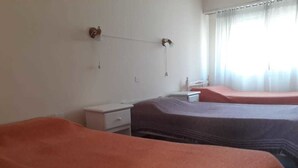 A hotel room with two beds, a small desk, and a window with curtains. - Departamentos MTD (Balcarce)
