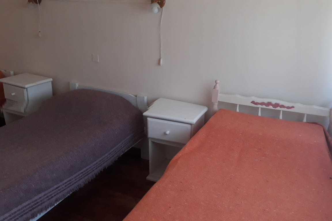 Een slaapkamer met twee enkele bedden, een witte nachtkastje en een witte dressoir.