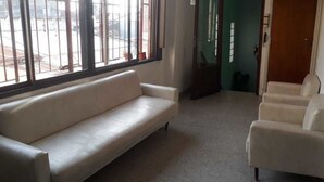 A room with a large window, a sofa, and a chair. - Departamentos MTD (Balcarce)
