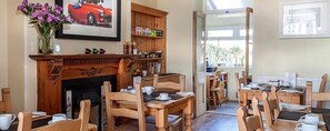 A dining area with wooden furniture, a fireplace, and a view of the outdoors. - The Olive Branch (St Ives)