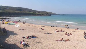 Une plage où des gens se prélassent au soleil et se baignent.