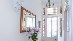 Un couloir avec un banc en bois, un miroir et un vase de fleurs.