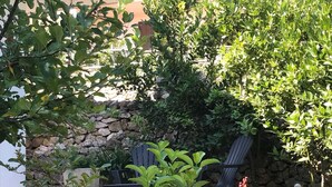 Jardí amb mur de pedra, dues cadires Adirondack i plantes amb flors.