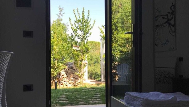 Habitació amb porta corredissa de vidre que dona a un jardí.