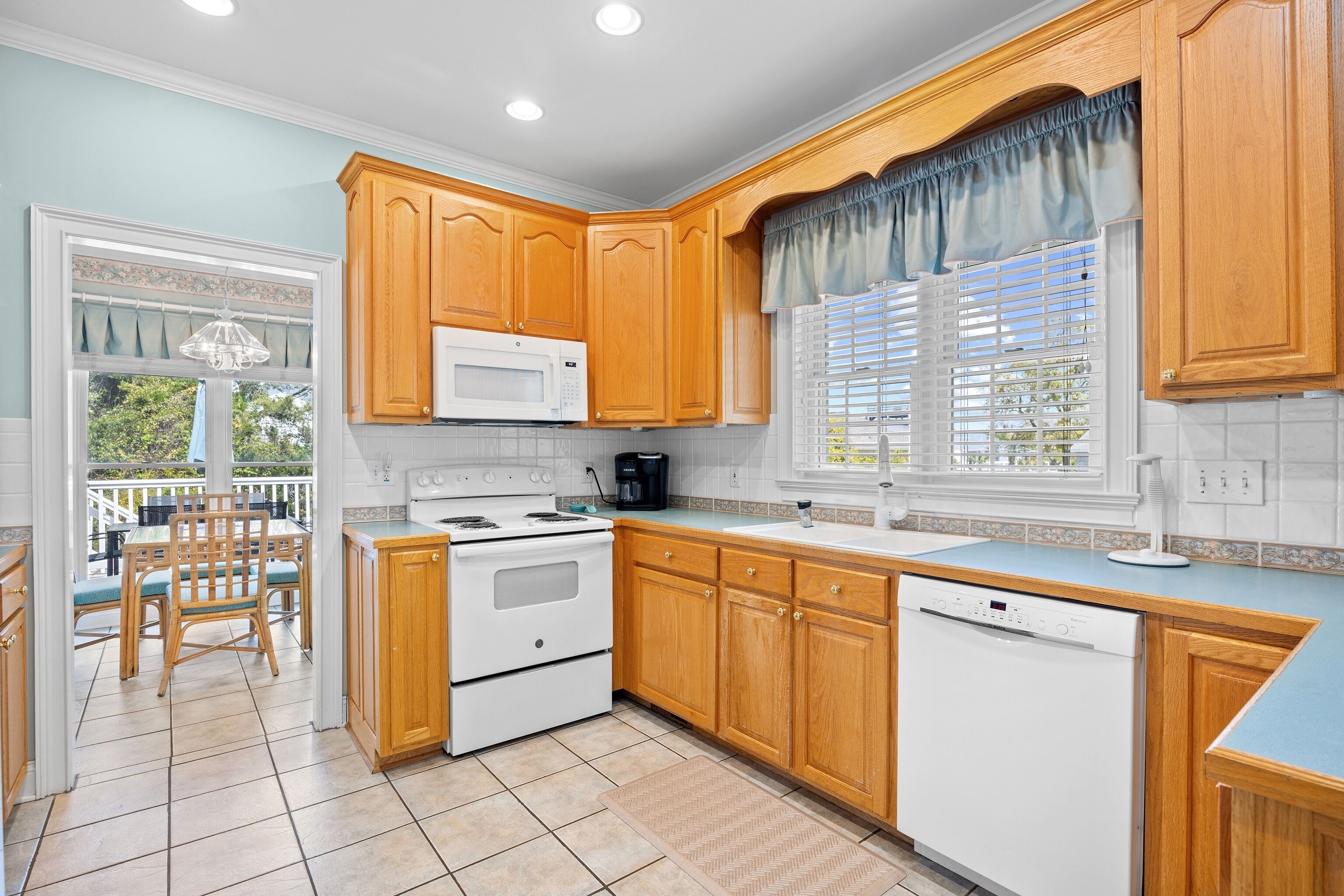A kitchen with wooden cabinets, a white stove, a microwave, and a dishwasher.