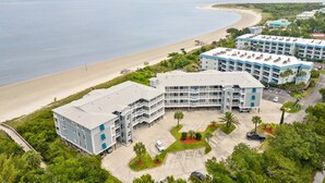 A beachfront hotel with multiple buildings, a parking area, and a view of the ocean. - Bay View Villas 105 | Waterfront, Community Pool (Tybee Island)